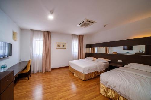 a hotel room with two beds and a television at Uptown Chinatown in Kuala Lumpur