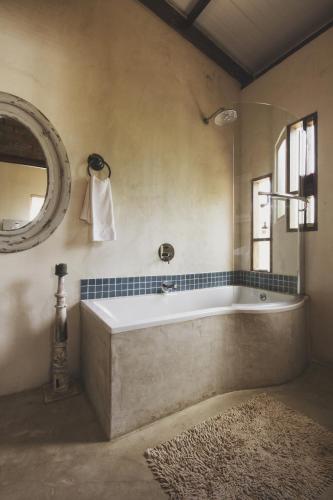 a bathroom with a tub and a mirror and a rug at A Hilltop Country Retreat in Swellendam