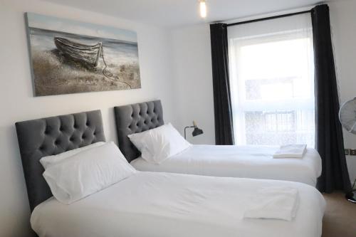 two beds in a room with a window at Garland Modern Central City Apartment London in London