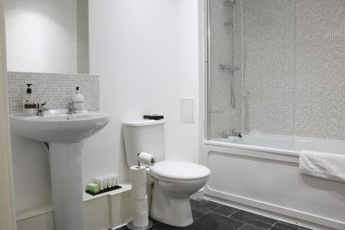 a white bathroom with a toilet and a sink at Garland Modern Central City Apartment London in London