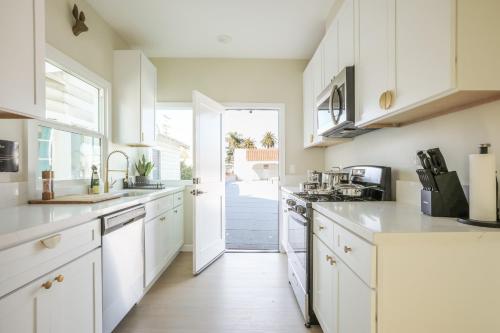 a kitchen with white cabinets and an open door at Cozy Sunny Brand-new Apt 1 Block From The Beach in Long Beach