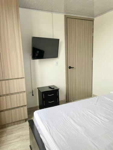 um quarto com uma cama e uma televisão de ecrã plano em Apacel em Cartago