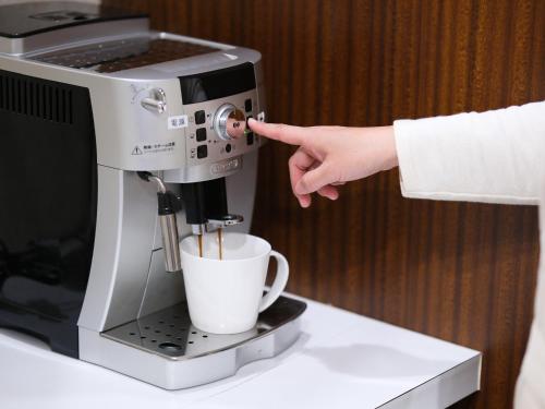 a person is pouring coffee into a coffee machine at Fukuyama Oriental Hotel in Fukuyama