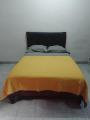 Una cama con una manta amarilla encima. en Departamento Escudero, en Tamazunchale