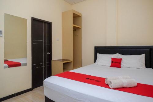 a bedroom with a large bed with a red blanket at RedDoorz near Taman Pantai Alam Indah Tegal in Tegal