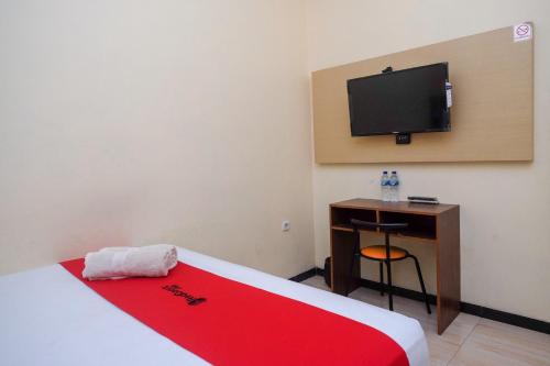 1 dormitorio con 1 cama y escritorio con TV en RedDoorz near Taman Pantai Alam Indah Tegal, en Tegal