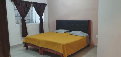 ein Schlafzimmer mit einem Bett mit einer gelben Decke und einem Fenster in der Unterkunft Departamento Escudero in Tamazunchale