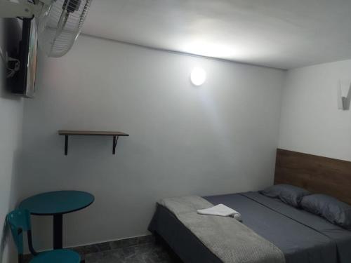ein Schlafzimmer mit einem Bett, einem Tisch und einem Stuhl in der Unterkunft HOTEL DEPARTAMENTAL in Ibagué
