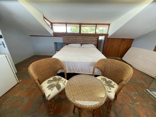 a bedroom with a bed and two chairs and a table at Prédio Histórico na Rio Branco in Caxias do Sul