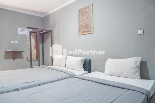 duas camas sentadas uma ao lado da outra num quarto em Crown Residence near Tugu Yogyakarta Mitra RedDoorz em Yogyakarta