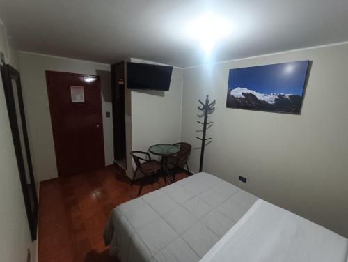 a bedroom with a bed and a table and a television at HOSTAL SAMAYWASI in Huancayo