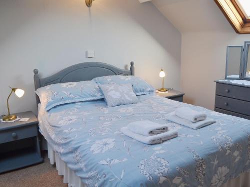 a bedroom with a blue bed with towels on it at Cyll Y Felin Fawr 1 in Aberdaron