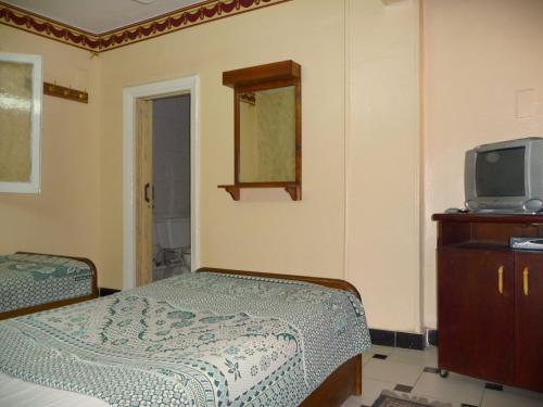 een slaapkamer met een bed, een tv en een dressoir bij Venus Hostel in Caïro