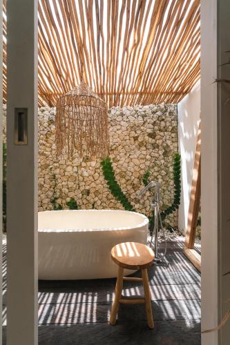 a bathroom with a tub and a stone wall at Amaka Villas in Uluwatu