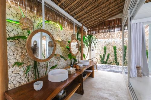 a bathroom with two sinks and mirrors on a stone wall at Amaka Villas in Uluwatu