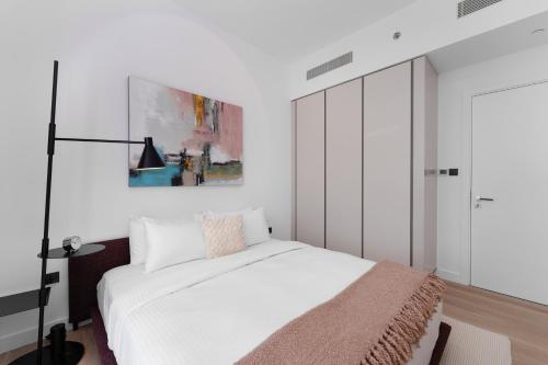 a bedroom with a white bed and a painting on the wall at Maison Privee - Deluxe 3BR Apt with Dubai Marina Vws & Beach Access in Dubai