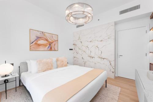 a white bedroom with a bed and a marble wall at Maison Privee - Deluxe 3BR Apt with Dubai Marina Vws & Beach Access in Dubai