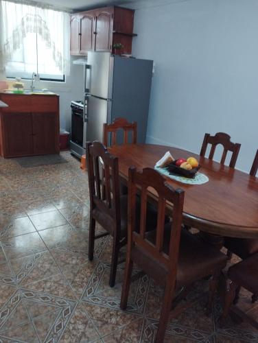 una cucina con tavolo in legno, sedie e un angolo cottura. di Departamento Amoblado en Urba. Ilo a Ilo