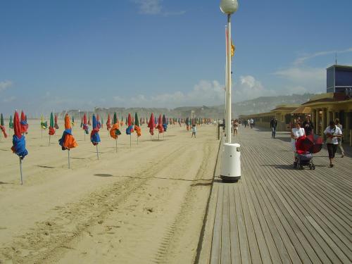 a beach with umbrellas and people walking on it at Les Roulottes de la Risle in Calleville
