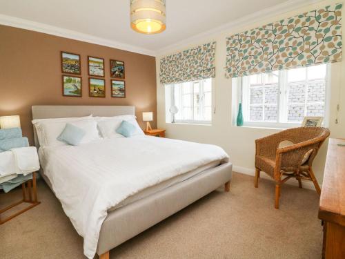a bedroom with a large white bed and two windows at Crab Cottage in Ilfracombe