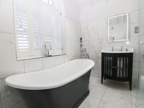 a white bathroom with a tub and a sink at Y Bwthyn Ty Du in Llannor