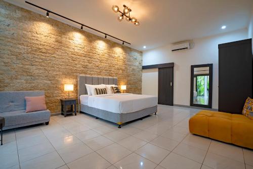 Villa Brezze - Nusa Dua في نوسا دوا: غرفة نوم بسرير وجدار من الطوب