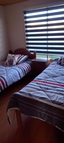 a bedroom with two beds and a window with blinds at Cabaña 1 lagunillas in Navidad