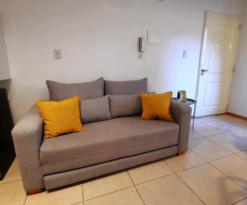 a gray couch with two yellow pillows in a living room at Departamentos René in Ciudad Lujan de Cuyo