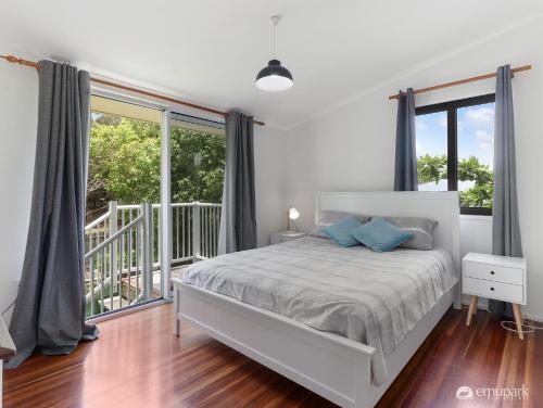 ein weißes Schlafzimmer mit einem Bett und einem Balkon in der Unterkunft Four Palm's in Emu Park