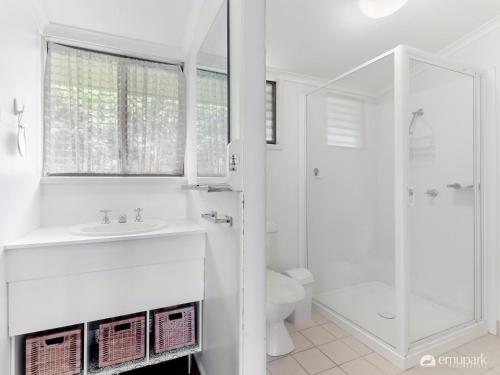 ein weißes Bad mit einem Waschbecken und einer Dusche in der Unterkunft Four Palm's in Emu Park