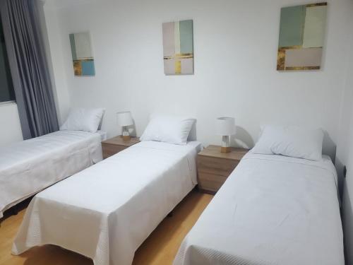 drie bedden in een kamer met witte muren en houten vloeren bij Bello Horizonte Departamento in Cuenca