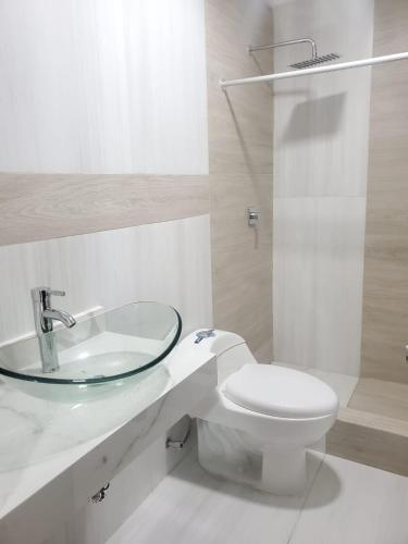 a white bathroom with a sink and a toilet at Bello Horizonte, Dep grande con parqueadero in Cuenca