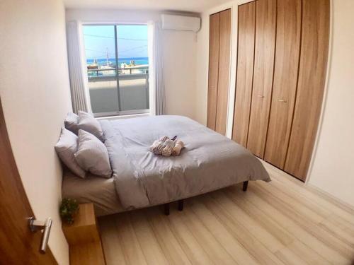 a bedroom with a bed with a stuffed animal on it at ZZOKIAI Premier Ou 奥武壹号A棟 奥武岛上能看见海的新建一户建 走到海滩只有1分钟 only 1 min walk to the beach in Shikenbaru