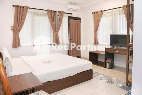a bedroom with a bed and a desk and a television at Panorama İnn Residence Batu Mitra RedDoorz in Batu