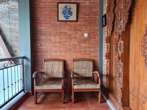 two chairs sitting on a porch next to a brick wall at Ndalem Suryo Saptono Guest House in Yogyakarta