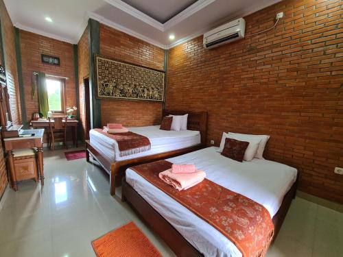 a bedroom with two beds and a brick wall at Ndalem Suryo Saptono Guest House in Yogyakarta