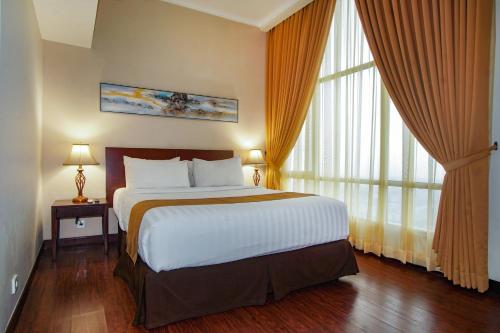 a bedroom with a large bed and large windows at Grand Dafam Ancol Jakarta in Jakarta