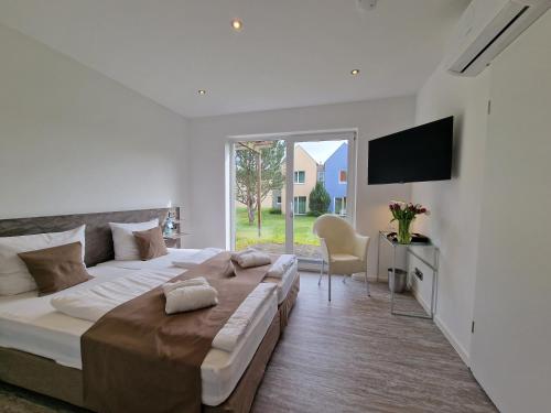 biała sypialnia z dużym łóżkiem i telewizorem w obiekcie Eurostrand Resort Moseltal w mieście Leiwen
