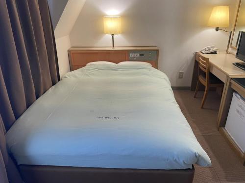 duże łóżko w pokoju hotelowym z biurkiem i łóżkiem o wymiarach sześciu w obiekcie Olympic Inn Kanda w Tokio