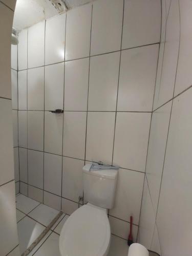 een badkamer met een toilet in een witte betegelde muur bij Apartamento em Maranduba - Ubatuba in Ubatuba