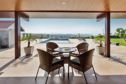 a patio with a table and chairs and a pool at Breezy Whispers by StayVista - Private infinity pool, Stunning mountain views, Spacious swimming pool, Deck & Lawn in Wādhiware
