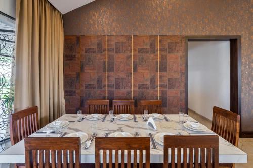 a dining room with a table with chairs and a tableablish at Breezy Whispers by StayVista - Private infinity pool, Stunning mountain views, Spacious swimming pool, Deck & Lawn in Wādhiware