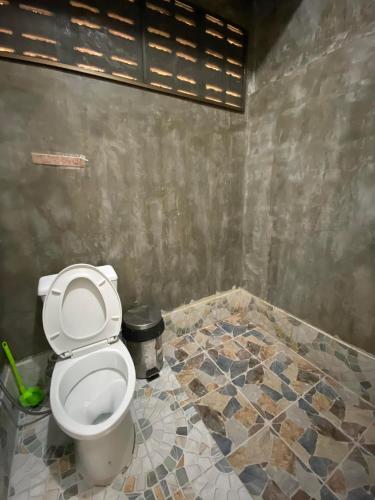 a bathroom with a toilet and a tiled floor at JJ&J Garden in Pai
