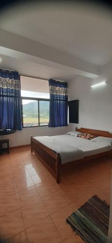 um quarto com uma cama grande e uma janela grande em Durga budget stay em Munnar