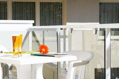 una mesa blanca y una silla con una flor. en Hotel Mon Pays, en Rímini