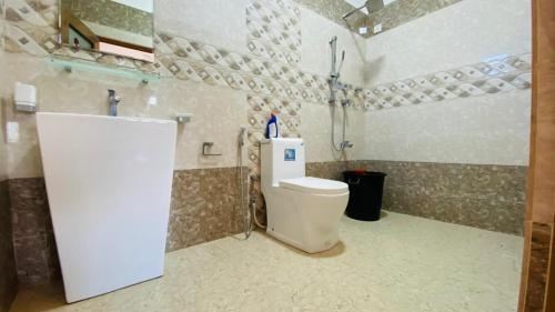 a bathroom with a white toilet and a sink at KPN Trinco Holiday Resort in Trincomalee