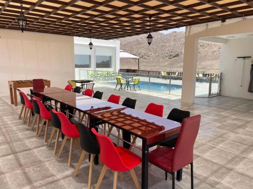 een eetkamer met een lange tafel en rode stoelen bij Jabal almumsi in Rasīs