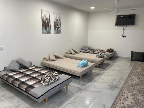 a room with three beds and a flat screen tv at Jabal almumsi in Rasīs