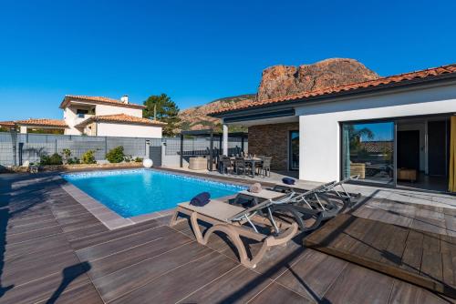 une cour arrière avec une piscine et une maison dans l'établissement Afa, proche d Ajaccio, Magnifique Villa 4 pers avec Piscine privée et vue montagne, à Afa