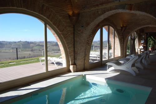 a swimming pool in a building with windows at Villa Fontana Relais Suite & Spa in Agliano Terme